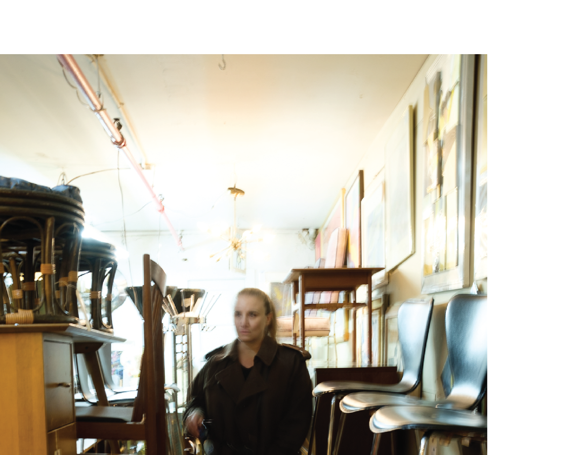 Portrait of interior designer Hallie Goodman sourcing among antique furniture