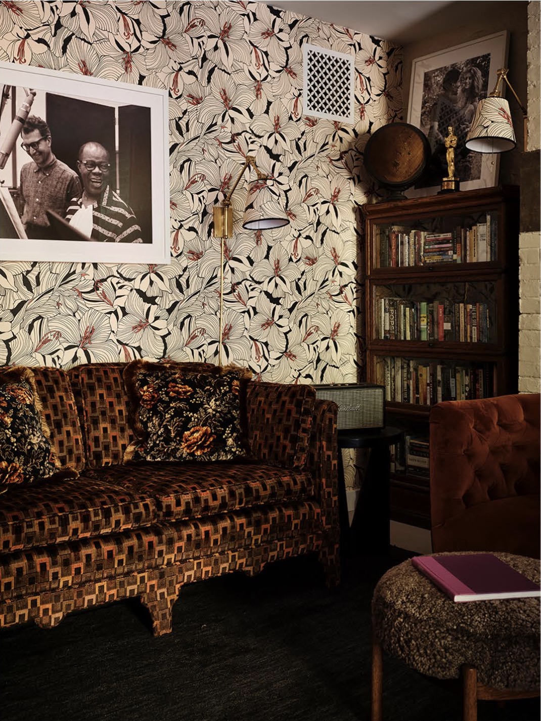 A collected sitting room with black-eyed-susan wallpaper, a patterned velvet sofa and a framed portrait